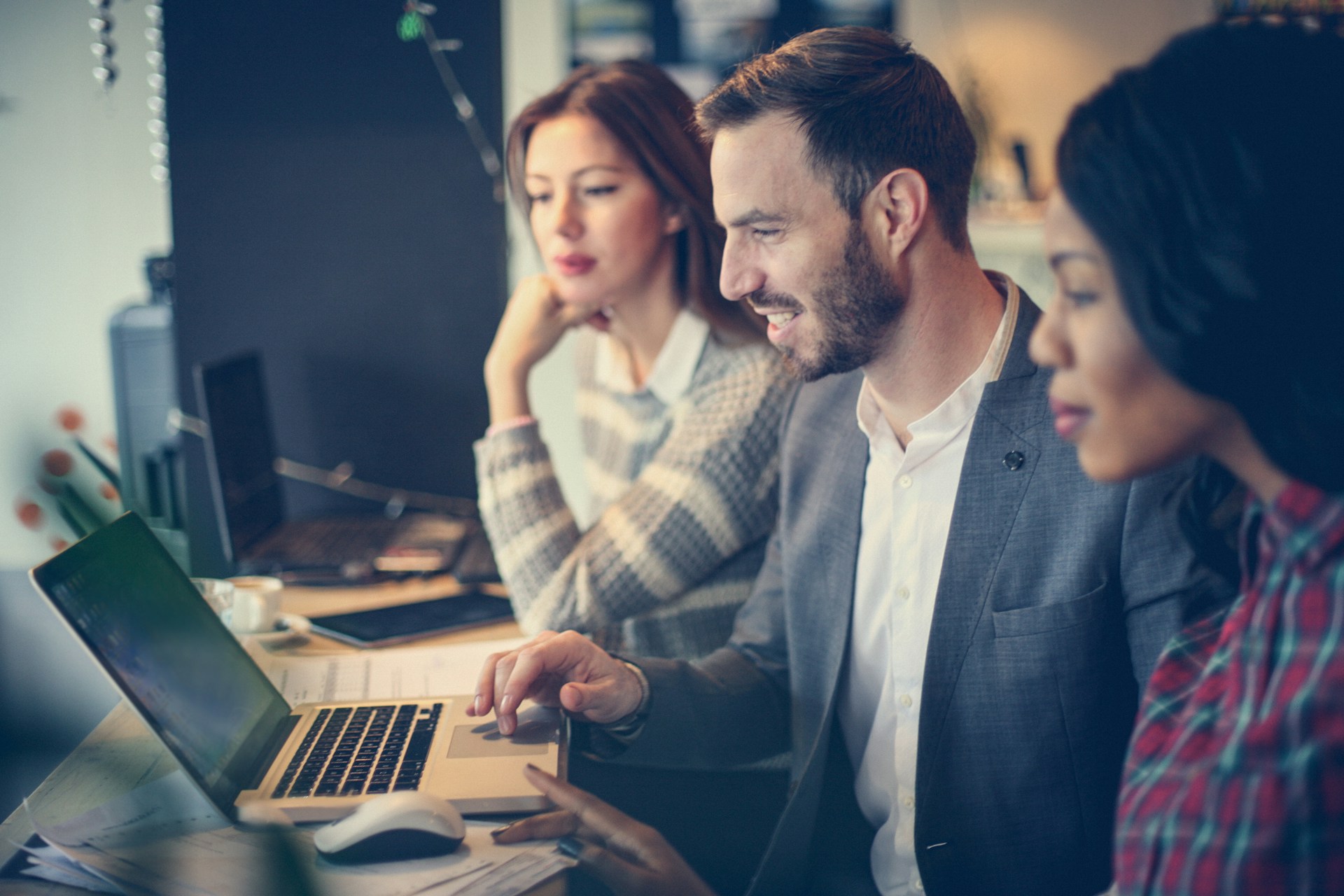 Drei Geschäftsleute sitzen vor einem Laptop und entwickeln gemeinsam Ziele.