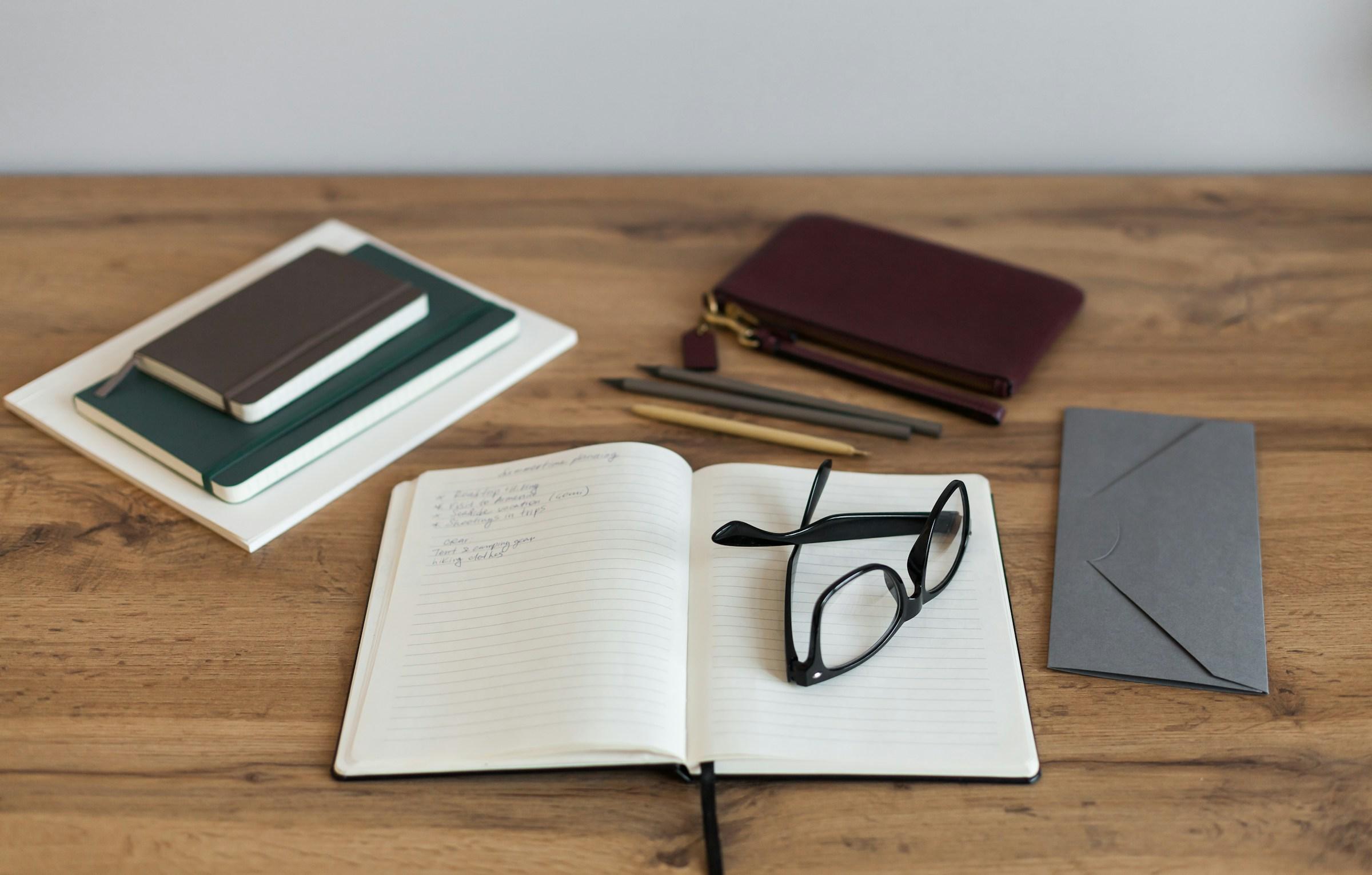 Notizbücher und Brille auf Tisch